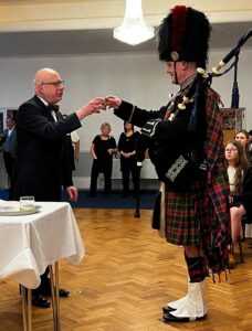 a wee dram with the piper at Burns Night dinner